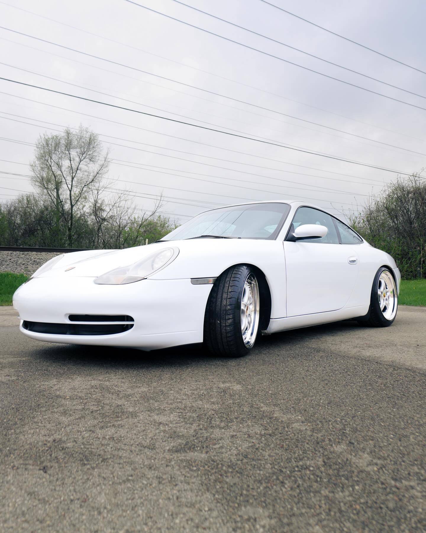 Front low angle outdoor profile view of white protected Porsche 911 Carrera