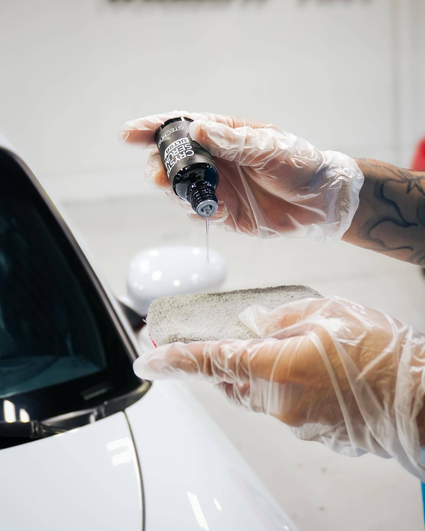 Technician applying Gtechniq Crystal Serum Ultra Ceramic Coating to the white Porsche body
