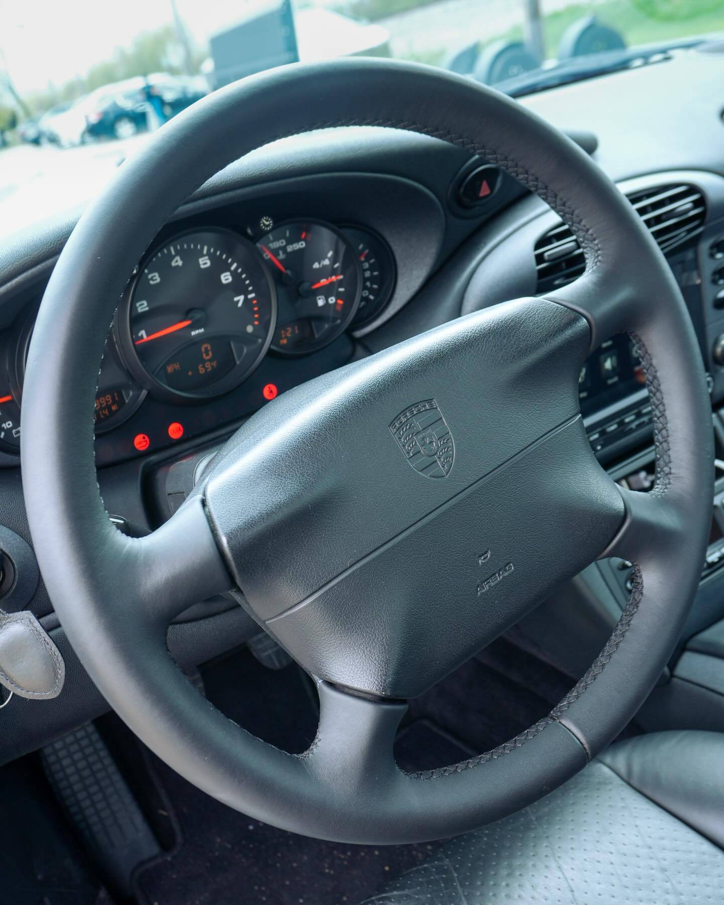 Black leather interior steering wheel and dashboard detail of Porsche 911