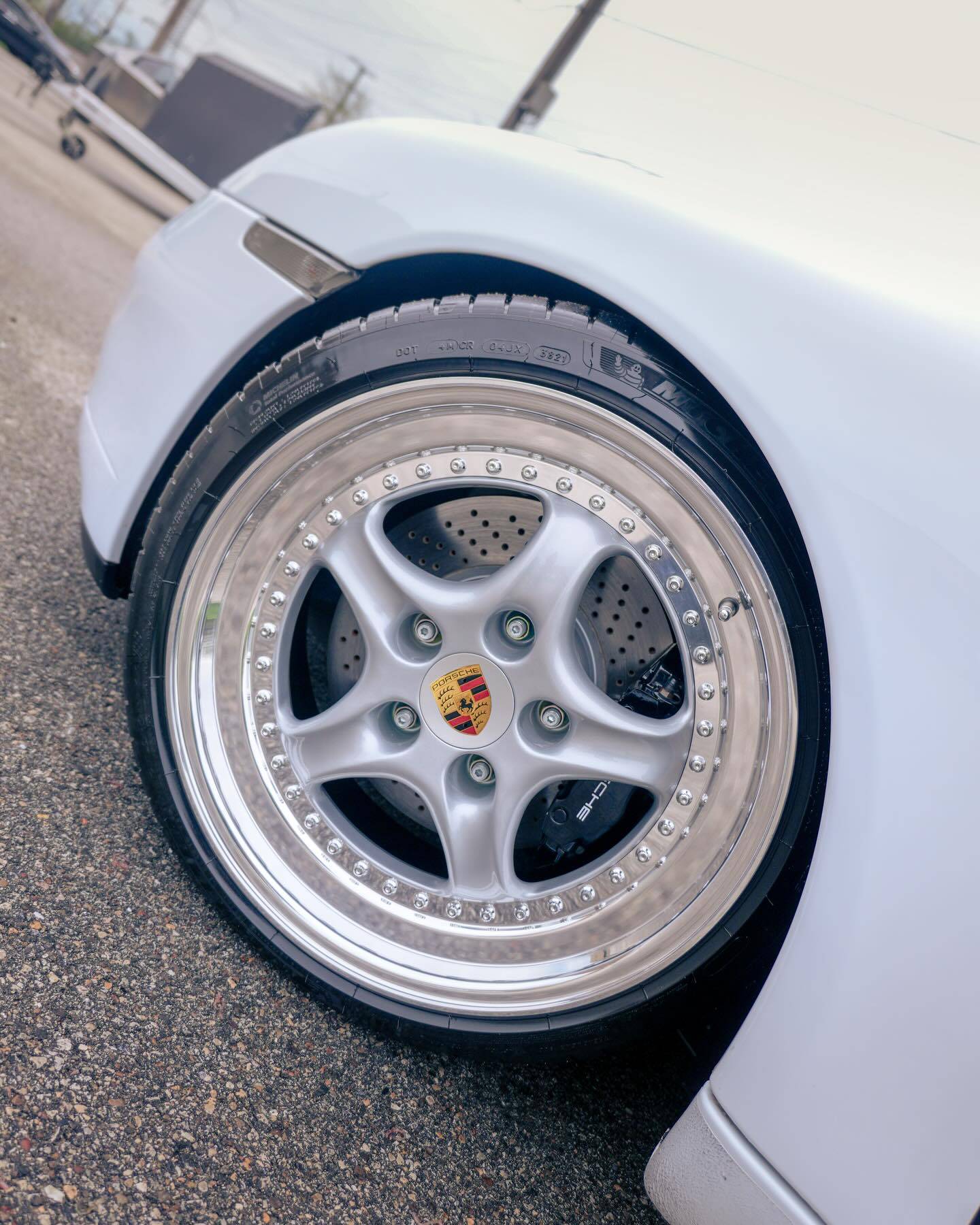 Deep dish chrome split wheel rim on white Porsche 911 close up