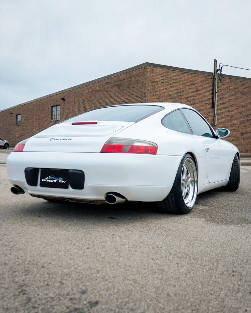 Rear profile view of white Porsche 911 Carrera with sleek ceramic tint outside shop