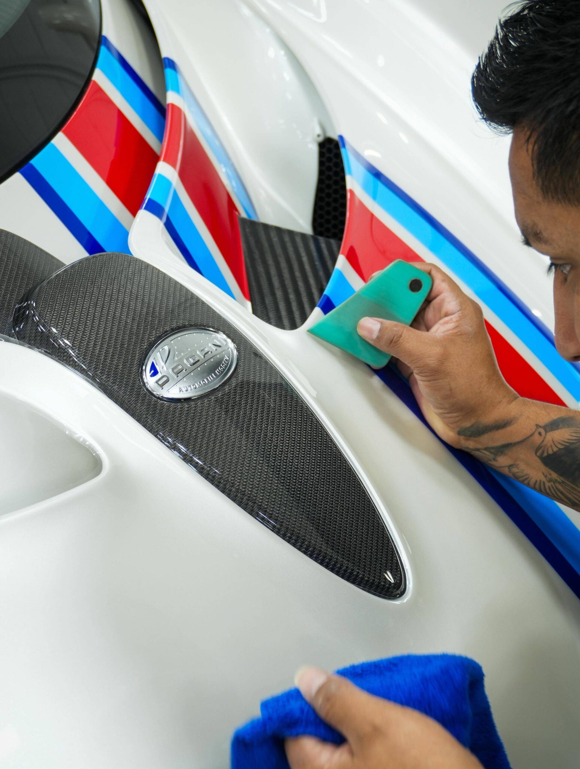 Squeegeeing clear bra film tightly around carbon fiber Pagani emblem details
