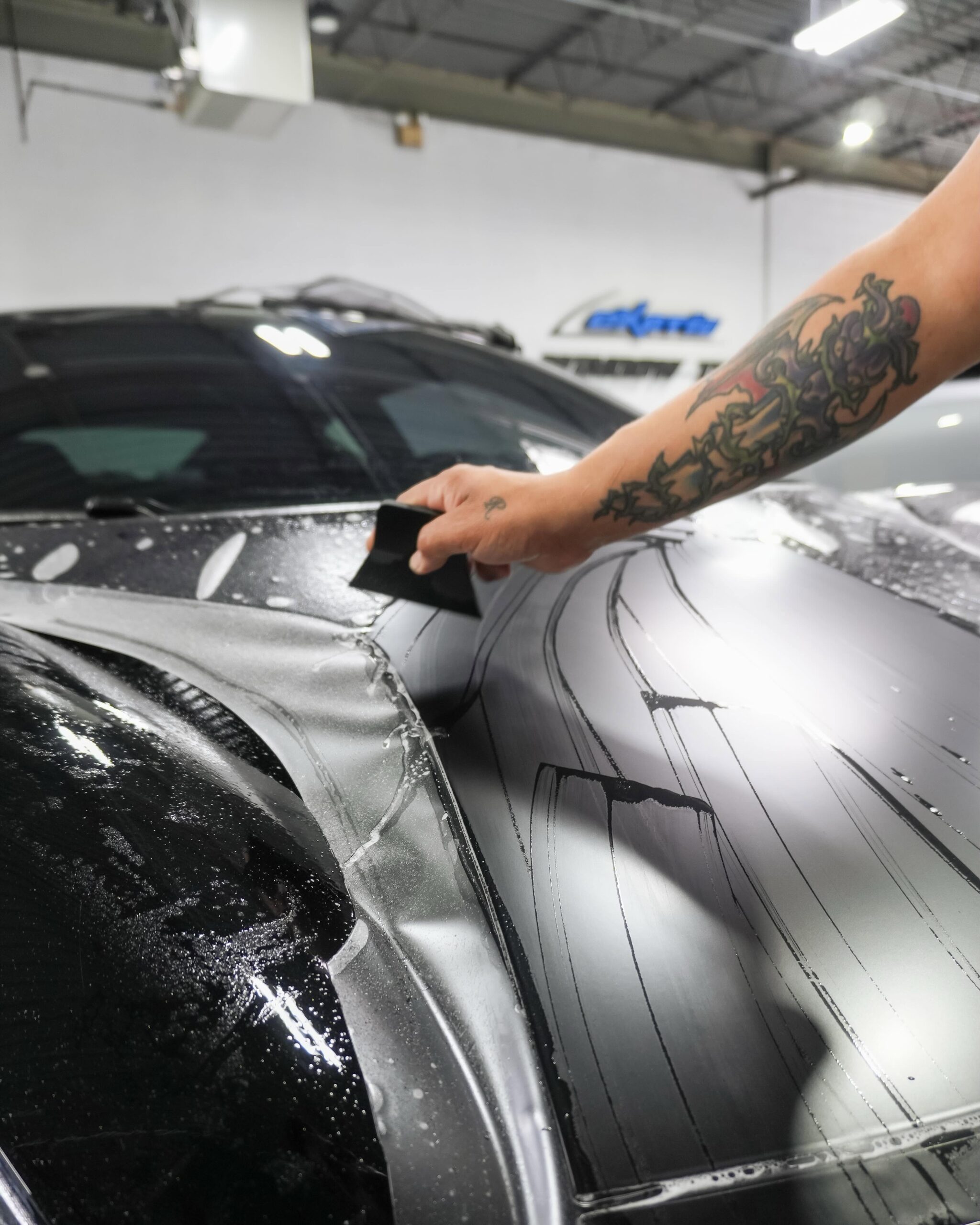 Artisan applying Paint Protection Film to Lotus Emira Hood