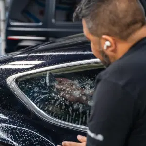 picture of man installing window tint on a car